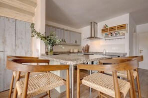 A kitchen with a central island, wooden chairs, and a vase with greenery. - Brisa & Mar, Las Chapas, 3-Bedroom (Marbella)