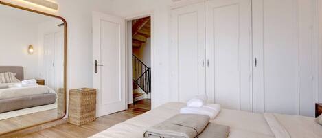 Un dormitorio con cama, un espejo grande, un armario y una escalera que sube a un piso superior.