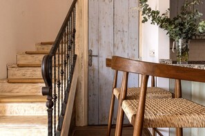 A wooden staircase with a black railing, a door with a metal handle, and a wicker chair with a woven seat and backrest. - Brisa & Mar, Las Chapas, 3-Bedroom (Marbella)