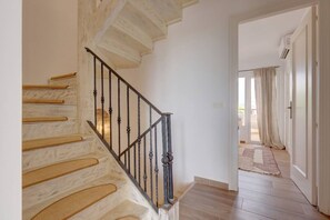 A staircase with wooden steps and a metal railing leading to a room with a white door and a view of the outdoors. - Brisa & Mar, Las Chapas, 3-Bedroom (Marbella)