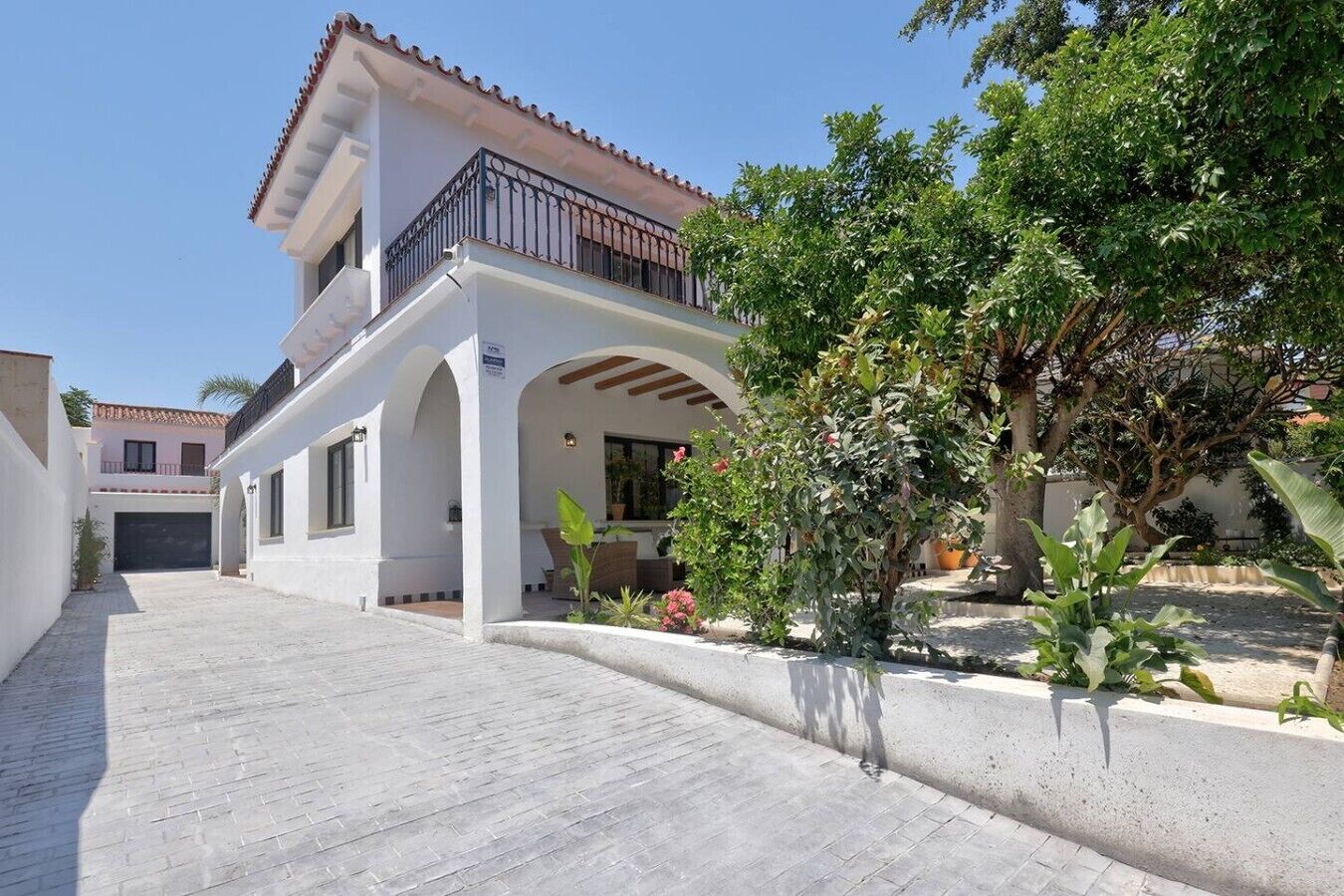 A two-story building with a balcony, a covered patio area, and a paved walkway.