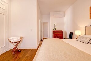 A hotel room with a bed, a wooden chair with towels, a nightstand, a lamp, and a red cabinet. - Villa Irene · Heated Pool · Pedregalejo (Málaga)
