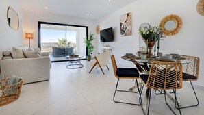 En moderne stue med sofa, spisebord, stole og et fjernsyn.