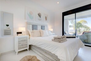 Een moderne slaapkamer met een groot bed, nachtkastjes en uitzicht op de natuur.