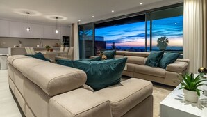 A modern living room with a sofa set, a coffee table, and a large window with a view of the sky. - Sky Penthouse with Private Pool (Artola)