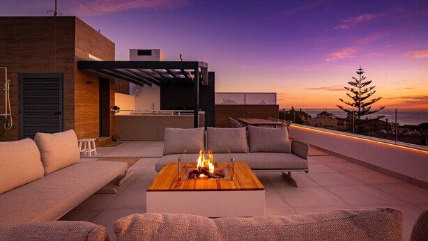 A rooftop terrace with a sofa set, a coffee table with a fire feature, and a view of the sunset. - Sky Penthouse with Private Pool (Artola)