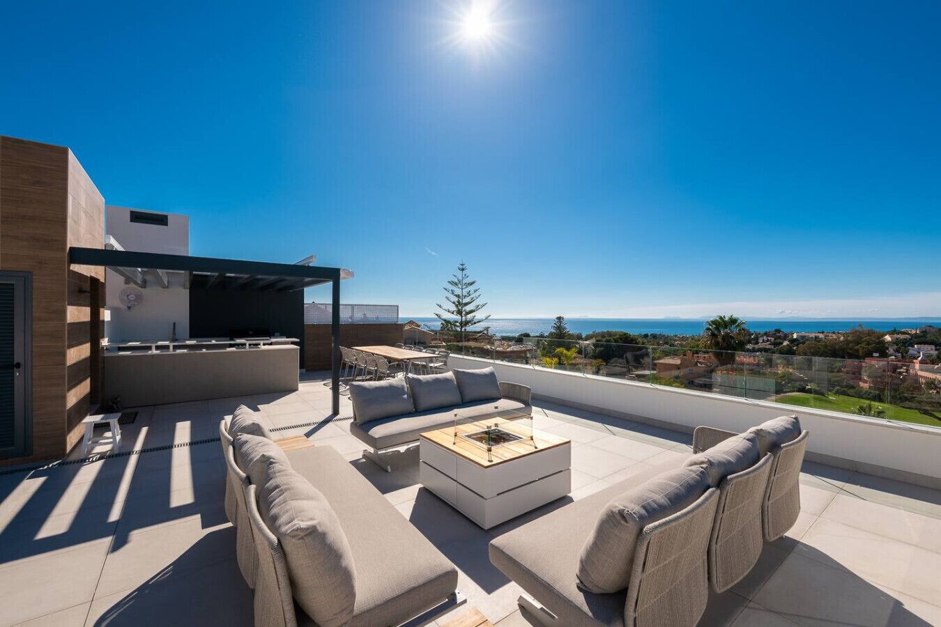 A rooftop terrace with outdoor furniture, a grill, and a view of the sea.