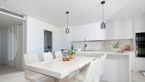 A modern kitchen with white cabinetry, a central island, and pendant lighting. - Sky Penthouse with Private Pool (Artola)
