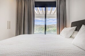 A bedroom with a large bed, a view of the outdoors, and a skylight. - Duplex Penthouse · Sea & Sky · Artola Alta (Marbella)