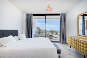 Ein modernes Schlafzimmer mit einem großen Bett, Blick ins Freie und einer besonderen Pendelleuchte.