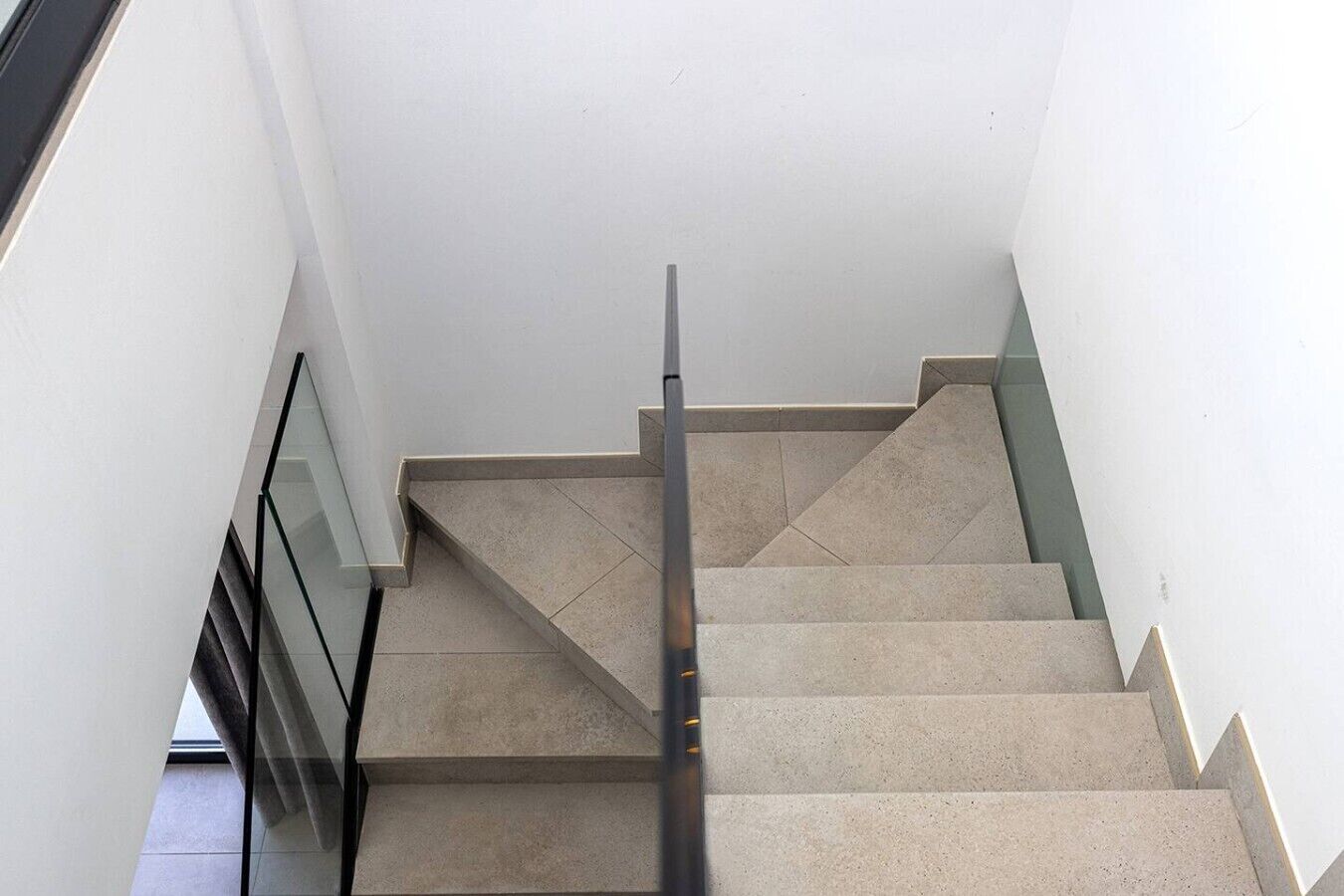 A staircase with a handrail, leading to a landing with a glass door.