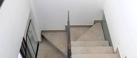 A staircase with a handrail, leading to a landing with a glass door.