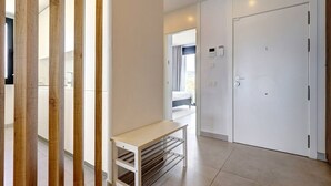 Et moderne hotelværelse med en skydedør i træ, et hvidt natbord og en stor, hvid garderobeskab.