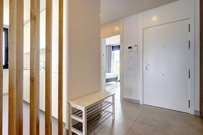 Ein modernes Hotelzimmer mit einer holzrahmenverkleideten Schiebetür, einem weißen Nachttisch und einem großen, weißen Kleiderschrank.