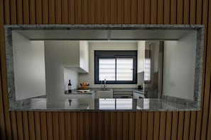 Uma cozinha moderna com ilha central, janela com persianas e revestimento de painéis de madeira.