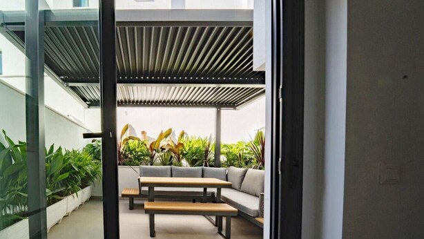 An indoor patio area with a seating arrangement, including a sofa and a table, surrounded by potted plants. - Charming Townhouse in Cancelada Village (Cancelada)