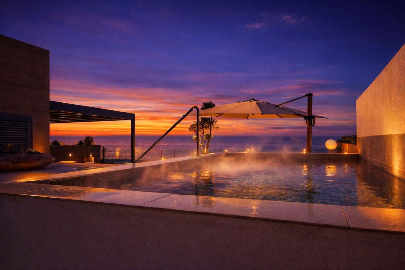 Zona de piscina con vistas al atardecer, un área de estar techada y un gran paraguas.