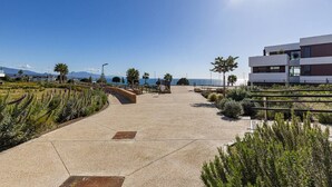 A coastal walkway with a clear view of the sea, a modern building, and landscaped areas with plants. - PAZ House with Views and a Garden (Málaga)