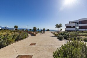 A coastal walkway with a clear view of the sea, a modern building, and landscaped areas with plants. - PAZ House with Views and a Garden (Málaga)
