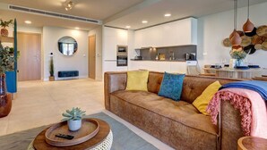 A modern living room with a sofa, a dining area, and a kitchen in the background. - PAZ House with Views and a Garden (Málaga)