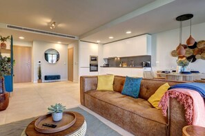 A modern living room with a sofa, a dining area, and a kitchen in the background. - PAZ House with Views and a Garden (Málaga)