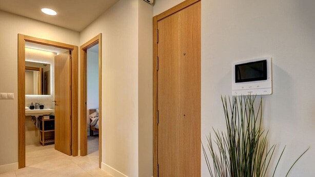 A hallway with wooden doors, a white wall-mounted TV, and a plant. - PAZ House with Views and a Garden (Málaga)