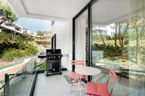 Ein Balkon mit Grill, Tisch und zwei Stühlen.