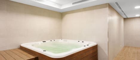 Un baño moderno con una bañera independiente, piso de madera e iluminación empotrada.