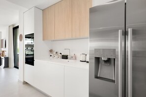 Eine moderne Küche mit weißen Schränken, einem Edelstahlkühlschrank und einem Wasserspender.