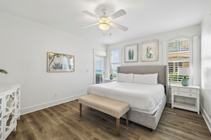 Ein Schlafzimmer mit Bett, Sitzbank, Deckenventilator und Kunstwerken an den Wänden.