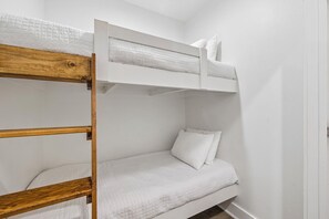 Ein Etagenbett mit Holzrahmen und weißer Bettwäsche.