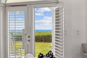 Ein Zimmer mit einer Tür, die auf einen Balkon mit Meerblick führt.