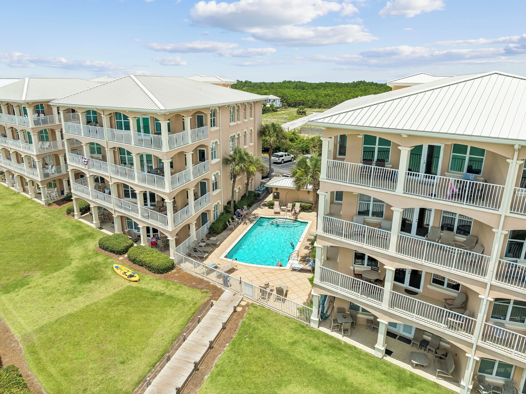 A multi-story hotel with balconies, a swimming pool, and a well-maintained lawn.