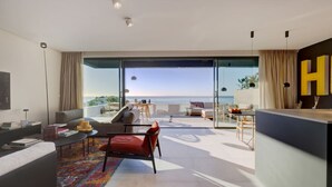 En moderne stue med et stort glasvindue, der fører ud til en balkon med havudsigt.