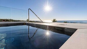 En swimmingpool med en solbeskinnelig himmel og frit udsyn til havet.