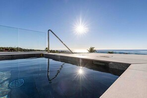 Ein Swimmingpool mit blauem Himmel und Blick auf den Ozean.