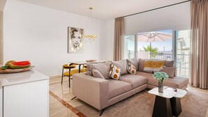A modern living room with a sofa, a dining table, and a view of the outdoors. - Luxury Family Penthouse, 7 Pools, Ocean View & Golf (Benahavís)