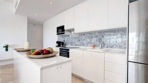 A modern kitchen with white cabinetry, a stainless steel refrigerator, and a tiled backsplash. - Luxury Family Penthouse, 7 Pools, Ocean View & Golf (Benahavís)