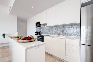 Eine moderne Küche mit weißen Schränken, einem Edelstahlkühlschrank und einer gefliesten Spritzschutzwand.