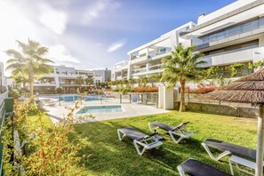 A modern hotel with a swimming pool, lounge chairs, and palm trees. - Modern apartment with a private garden (Málaga)