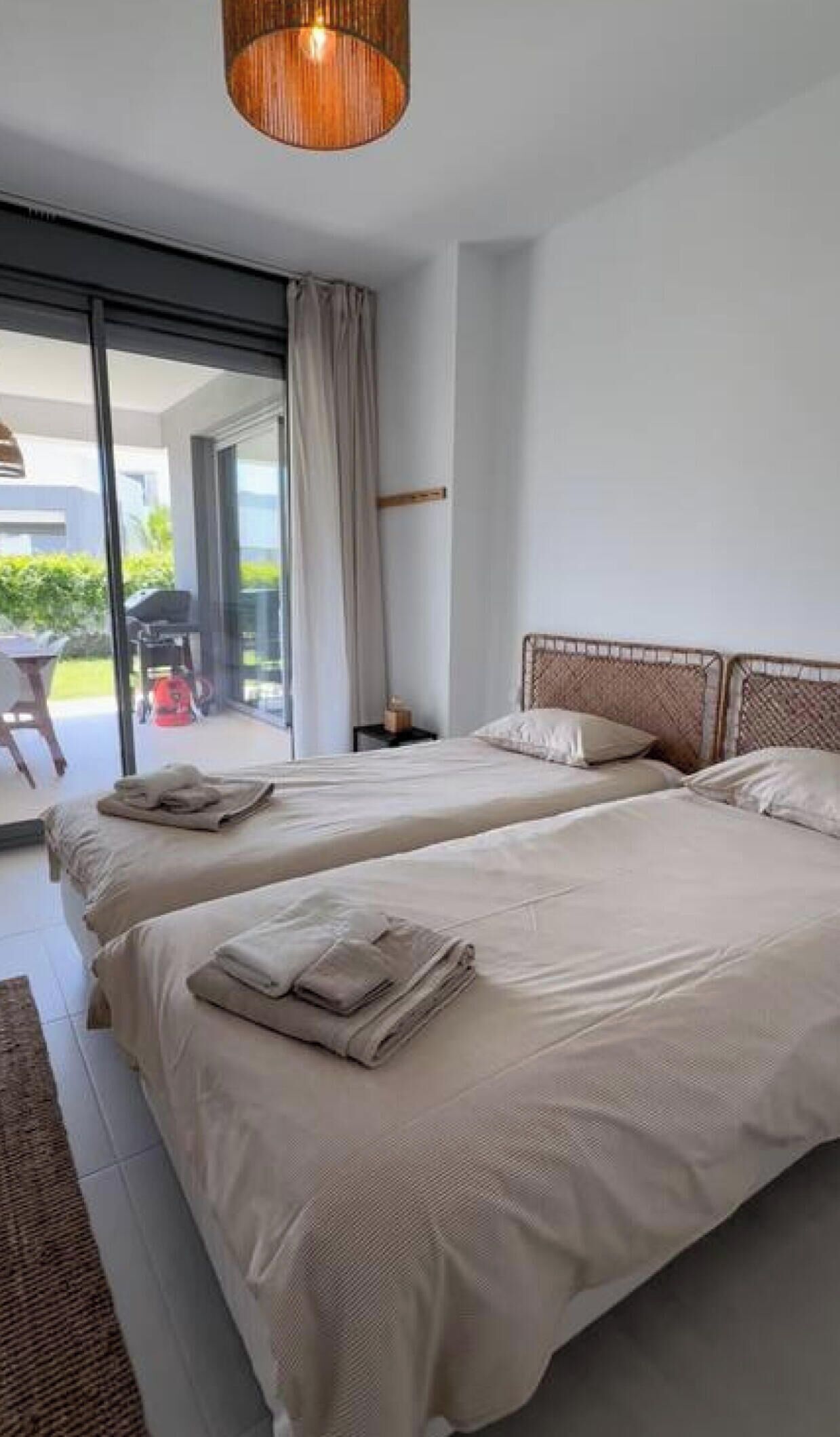 A modern bedroom with two beds, a large window, and a view of the outdoors.