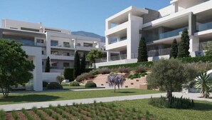 A modern multi-story residential building with balconies, surrounded by landscaped gardens and trees. - Modern apartment with a private garden (Málaga)