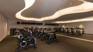 A gym with multiple exercise bikes arranged in rows, a wall-mounted rack of weights, and a ceiling with recessed lighting. - Modern apartment with a private garden (Málaga)