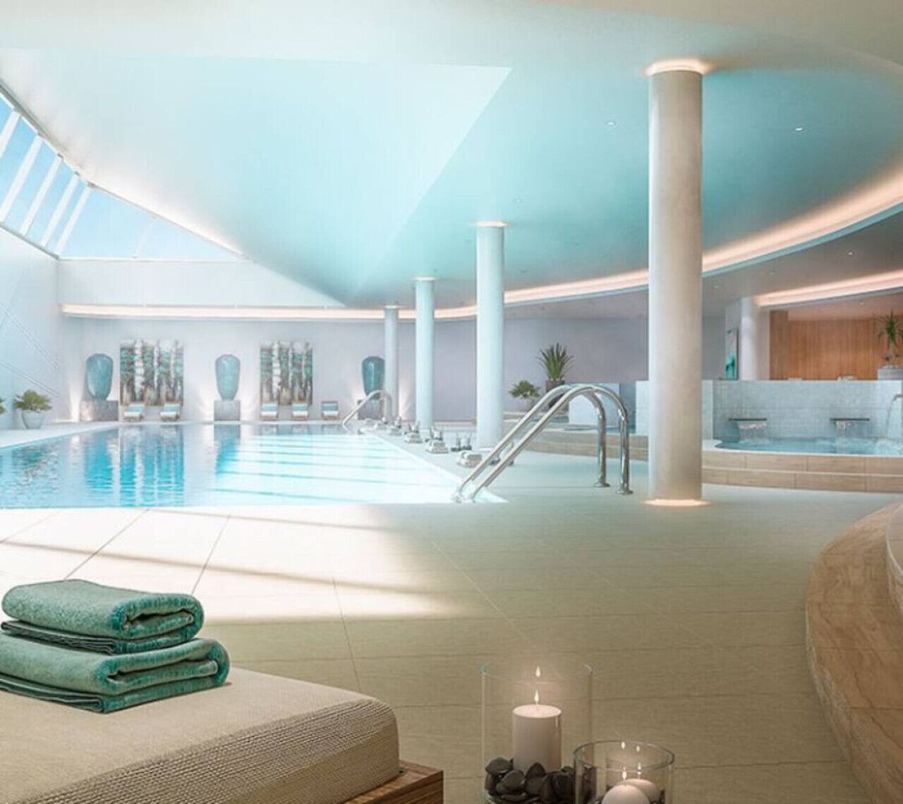Une vaste piscine intérieure à l’eau claire, entourée de piliers blancs et dotée d’un design moderne.