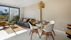 A modern living room with a dining area, large windows, and a view of the outdoors. - Modern apartment with a private garden (Málaga)