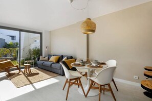 Ein modernes Wohnzimmer mit Essbereich, großen Fenstern und Blick ins Freie.