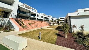 A modern building with multiple levels, outdoor seating areas, and a landscaped courtyard. - Modern apartment with a private garden (Málaga)