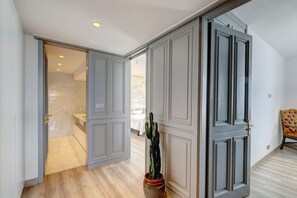 A hallway with a door leading to a bedroom, a potted plant, and a chair. - Marbella La Ola: 18th Floor (Marbella)
