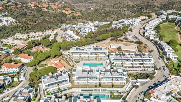 A residential area with modern buildings, a winding road, and a mountainous backdrop. - Luxury Apartment with Ocean View (Marbella)
