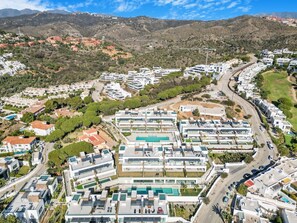 A residential area with modern buildings, a winding road, and a mountainous backdrop. - Luxury Apartment with Ocean View (Marbella)